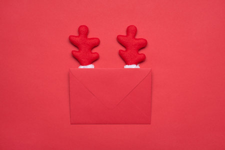 Photo close up picture of funky joke comic envelope with red fluffy deer horns isolated red bright monochrome backgroundの写真素材