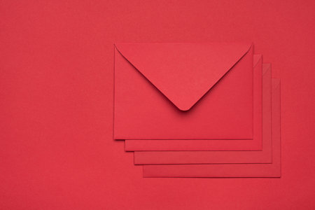 Top layout flatlay close up view photo of heap pile stack of four envelopes isolated red backdrop with empty spaceの写真素材