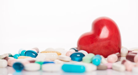 Drugs for heart concept. Close up view photo of red bright heart lying in heap pile stack of multicolored pills with copy space on white backdropの写真素材