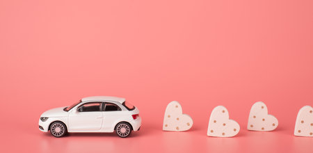 Congratulations on st valentine day concept. Side profile close up view photo of mini modern car riding and leaving behind small hearts isolated light tone backdrop with place for headerの写真素材