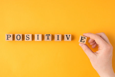 Think positively concept. Close up pov flatlay view photo of female hand putting last letter in word positive in a line isolated vivid color backdropの写真素材