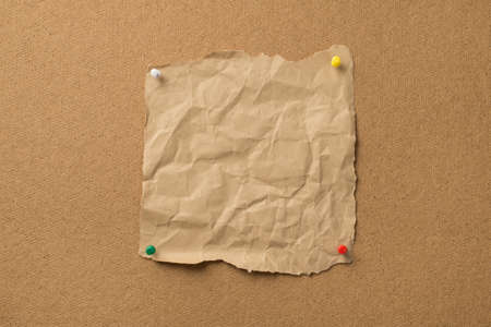 Photo of rumpled old craft piece pf paper attached to the wooden board with pinsの写真素材