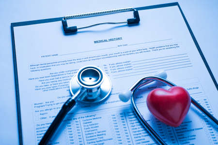 Close up photo of patient medical history card on the clipboard stethoscope equipment and small red...