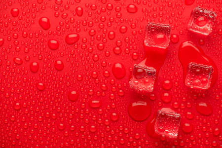 Top above overhead close up macro view photo of melting ice cubes on bright vivid color red background with dropsの写真素材