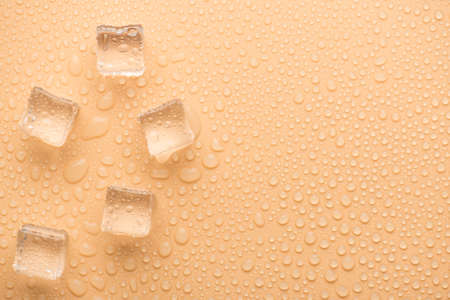 Top above overhead close up view photo ice cubes with rain drops on pastel color beige backgroundの写真素材
