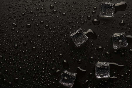 Top above overhead close up view photo of transparent ice cubes on black backdrop with empty blank...