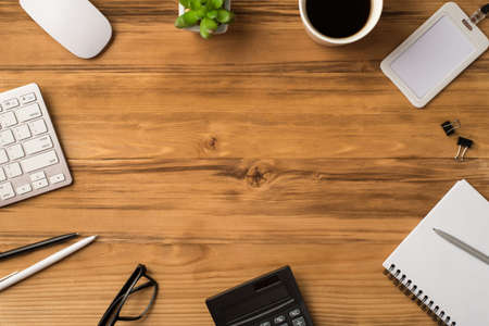 Above overhead flat lay view photo of office items objects with computer mouse mug with coffee binder clips notebook isolated light brown desk with empty spaceの写真素材