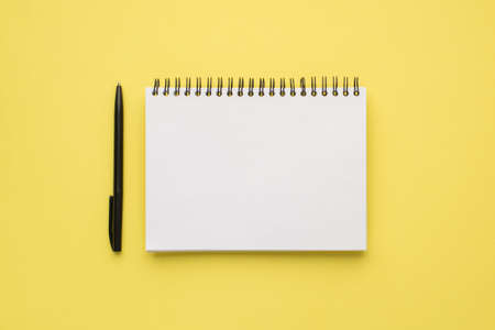 Photo overhead of notebook and black pen isolated on the yellow background