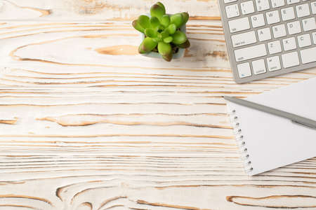 Photo above of keyboard plant notepad pen on the wood tableの写真素材