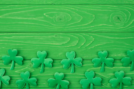 Overhead above flatlay view photo of bright green color clover leaves isolated wooden backdrop with...