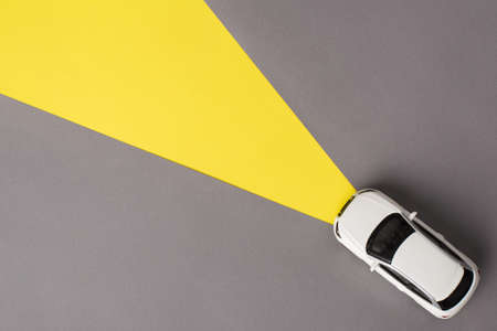 Top flat lay view photo of toy mini car driving on gray road with headlights on isolated background with copy empty spaceの写真素材