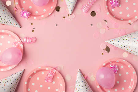 Top view photo of birthday composition with pink ribbon stars serpentine hats paper plates balloons and confetti on isolated pastel pink background with copyspaceの写真素材