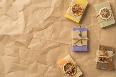 Top view photo of organic solid care products in paper wrapping and twine with dried citrus slices lavender cinnamon on isolated crumpled craft paper background with copyspaceの写真素材