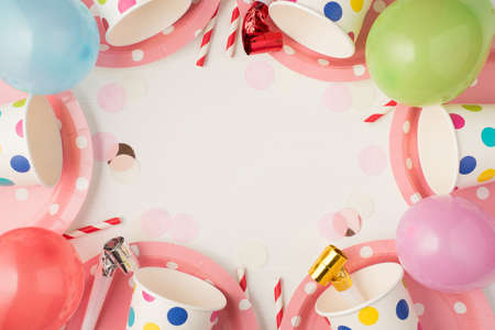 Overhead photo of cups plates party tubules whistle and balloons isolated on the white background with blank spaceの写真素材