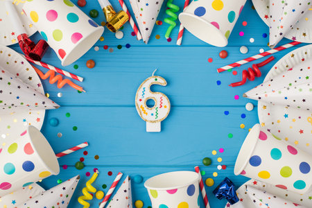 Top view photo of birthday candle for cake topper number six in the middle of birthday composition and party accessories on isolated blue wooden table backgroundの写真素材