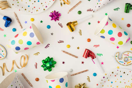 Above photo of cups plate confetti candles bows and party whistle isolated on the white backgroundの写真素材
