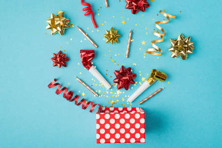 Top view photo of birthday composition blast of tinsel sparkles serpentine red yellow golden ribbon stars pipes and candles on isolated blue background with copyspaceの写真素材