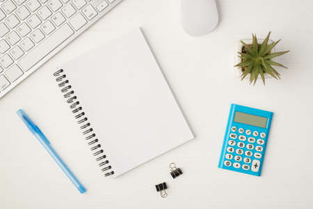 Top view photo of business workplace with keyboard mouse plant binders notebook with copyspace blue calculator and pen on isolated white backgroundの写真素材