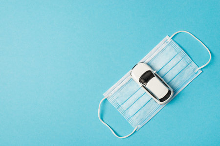 Top view photo of car model on medical face mask on isolated pastel blue background with copyspaceの写真素材