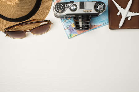 Top view photo of sunglasses headwear camera map and plane model on passport cover on isolated wooden white background with copyspaceの写真素材