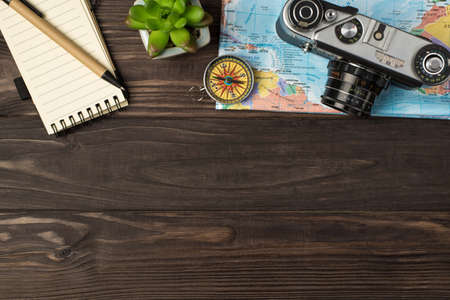 Top view photo of camera and compass on map notebook pen plant on isolated wooden table background with copyspaceの写真素材