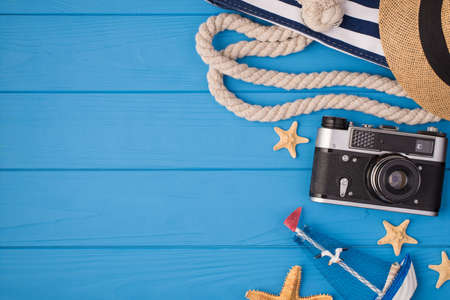 Above photo of bag sunhat camera starfish and ship isolated on the blue wooden background with copyspaceの写真素材