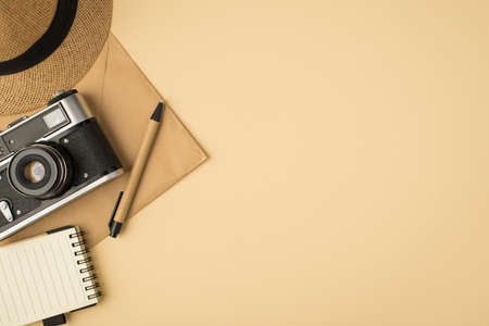 Top view photo of cap pen copybook and camera on craft paper envelope on isolated beige background with copyspaceの写真素材