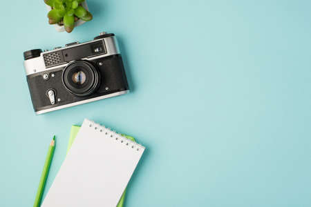 Top view photo of flowerpot camera and notebooks and green pencil on isolated pastel blue background with copyspaceの写真素材