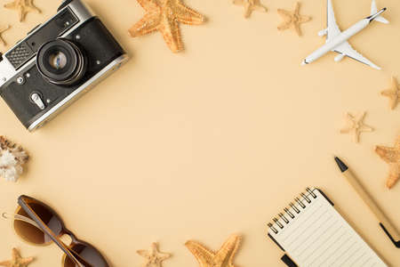 Top view photo of camera sunglasses plane model notebook pen seashell and starfishes on isolated beige background with copyspace in the middleの写真素材