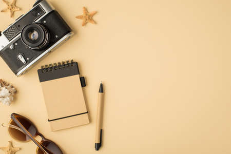 Top view photo of camera notebook pen sunglasses seashell and starfishes on isolated beige...