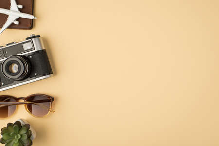 Top view photo of plane model on passport cover camera sunglasses and plant on isolated beige background with copyspaceの写真素材