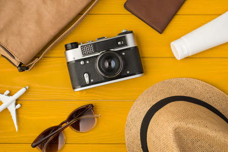 Above photo of sunhat camera bag sunglasses passport sunblock and airplane isolated on the yellow wooden backgroundの写真素材
