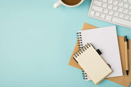 Top view photo of white keyboard cup copybooks and pen on isolated pastel blue background with...