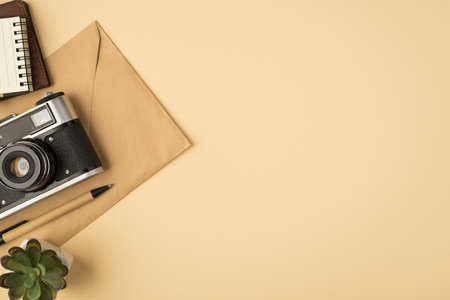 Top view photo of camera copybook on passport cover craft paper envelope pen and plant on isolated beige background with copyspaceの写真素材