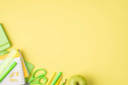 Above photo of notebook pen pencil felt-tip scissors ruler paperclips and apple isolated on the...