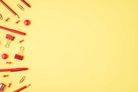 Overhead photo of red marker paperclips pen pencil and sharpener isolated on the yellow background with blank spaceの写真素材