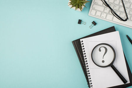 Top view photo of notepads sticker with interrogation mark magnifier glass binders pen plant glasses and keyboard on isolated pastel blue background with copyspaceの写真素材