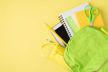 Above photo of backpack ruler notepad pen pencil tablet and pencil-box isolated on the yellow backgroundの写真素材