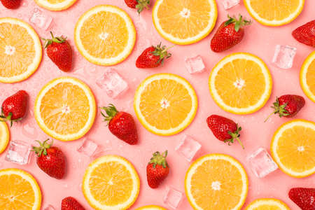 Top view photo of strawberries orange slices ice cubes and water drops on isolated pastel pink backgroundの写真素材