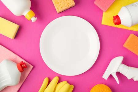 Top view photo of white clean plate in the middle scouring pads rags rubber gloves and white...