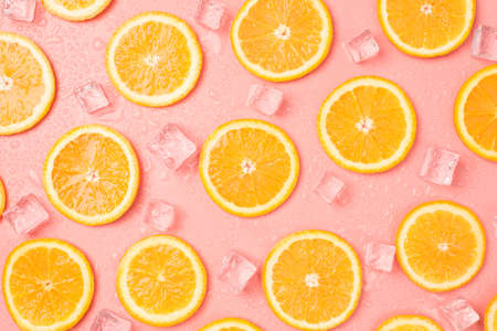 Top view photo of orange slices ice cubes and drops on isolated pastel pink backgroundの写真素材