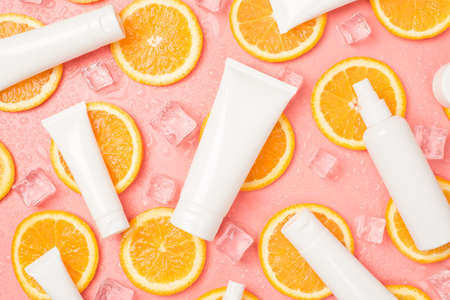 Top view photo of white cream tubes and spray bottle orange slices ice cubes and drops on isolated...