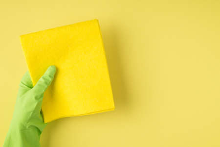Overhead pov photo of cleaning rag and green gloves isolated on the yellow backgroundの写真素材