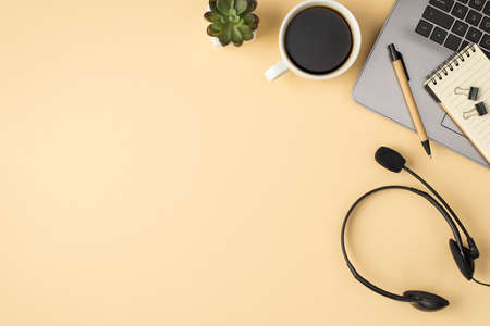 Overhead photo of laptop notebook pen paperclips plant cup of coffee and headphones