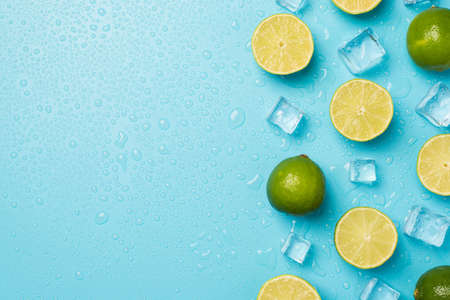 Above photo of heap of limes cubes of ice and drops isolated on the blue background with empty spaceの写真素材
