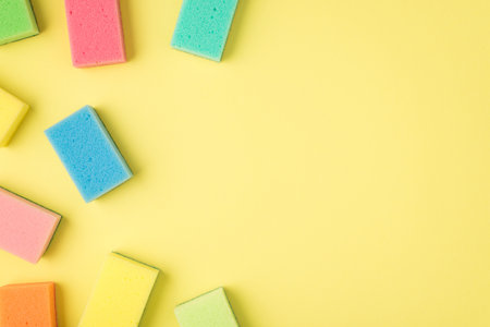 Top view photo of multicolor sponges on isolated yellow background with copyspace on the rightの写真素材