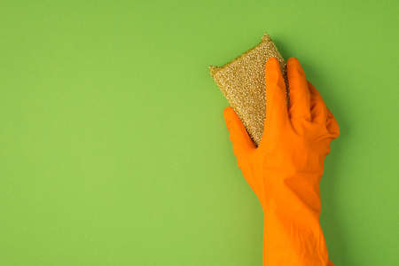 Above photo of cellulose sponge and orange gloves isolated on the green backgroundの写真素材