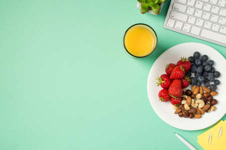 Top view photo of workplace keyboard plant sticker note paper pen glass of juice and plate with...
