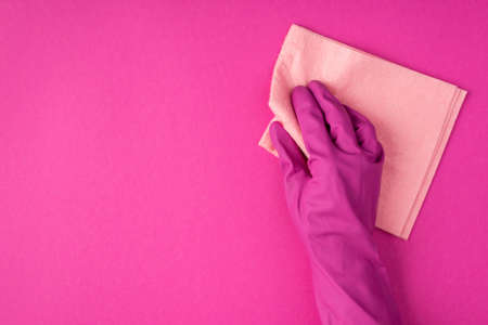 Top view photo of hand in pink glove using pastel pink napkin on isolated pink background with blank spaceの写真素材