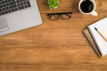 Top view photo of laptop plant glasses cup of coffee and pen on two planners on isolated wooden table background with copyspaceの写真素材